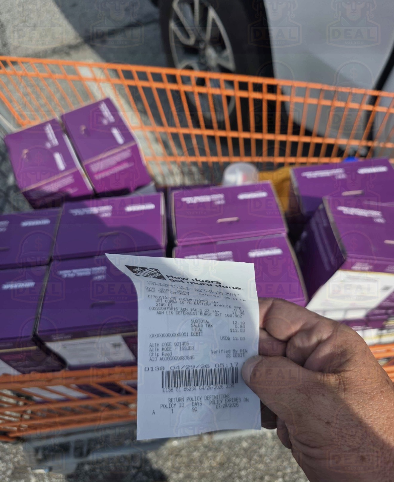 Home Depot cart in the parking lot loaded with 21 purple USI smoke and CO detector two-packs, receipt held over the boxes.